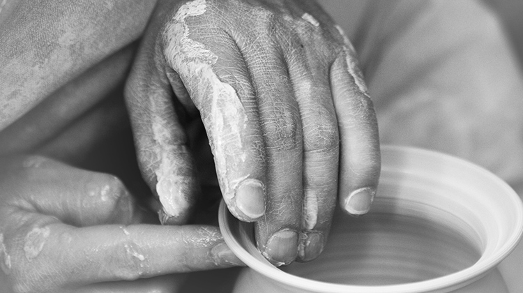 Hands working clay into pottery