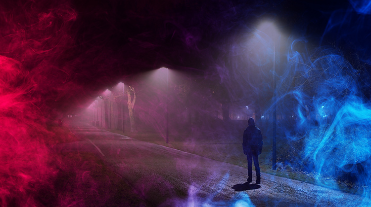 Man walking down dark path with colorful fog