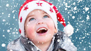 A young child looking up at snow falling